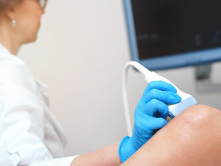 Probe placed on a patient’s knee during MSK ultrasound training, with the scan on screen